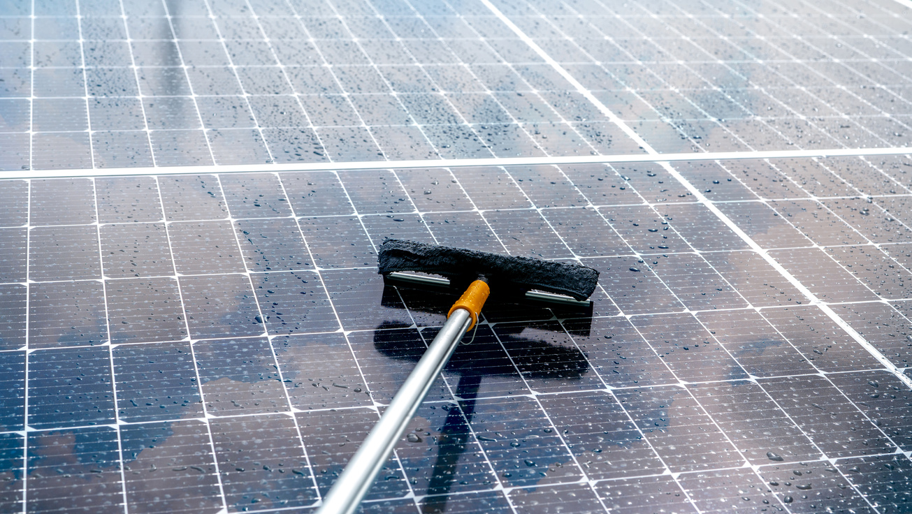 Cleaning solar panel with microfiber mop on wet roof. Solar pane